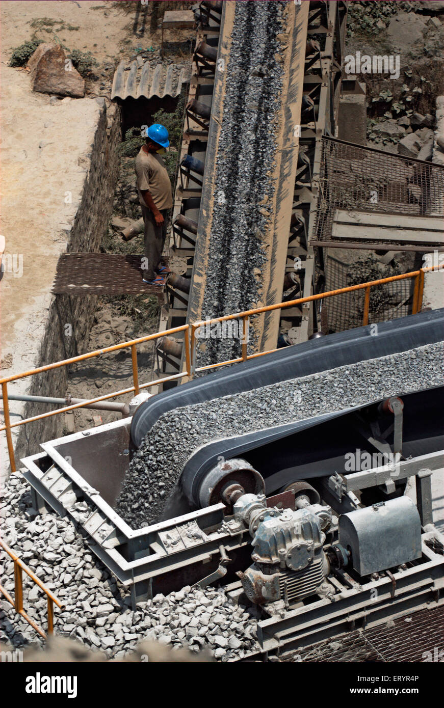 Worker inspecting crushed stones on conveyor belt on bypass site ; Madras Chennai ; Tamil Nadu ; India 17 July 2008 Stock Photo