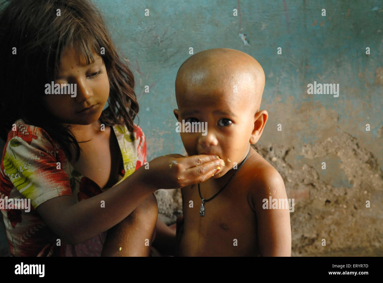 Girl feeding younger brother , Bombay , Mumbai , Maharashtra , India , Asia Stock Photo