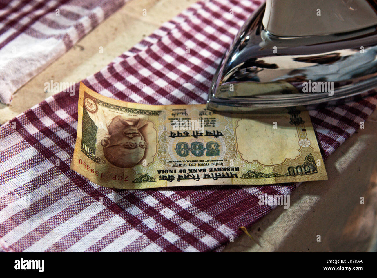 Devotee ironing wet currency note offering to lalbaug cha raja after ganpati festival ; Bombay Mumbai Stock Photo