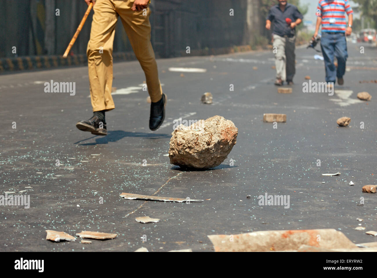 Policeman running , stones pelted on road ; Bandra ; Bombay , Mumbai ; Maharashtra ; India , Asia Stock Photo