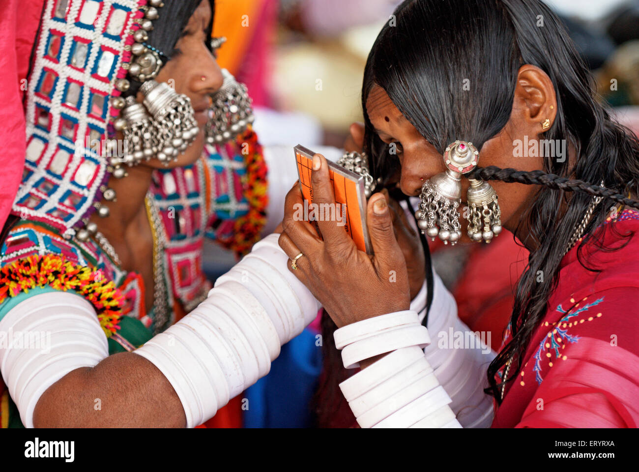 Banjara gypsy nomad tribal woman wearing silver jewelry looking in mirror , Nanded , Maharashtra , India , Asia Stock Photo