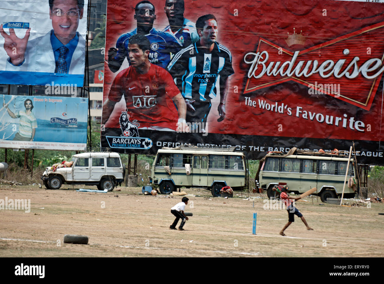 Children playing cricket in front of hoarding showing international football player 4 May 2008 NO MR Stock Photo