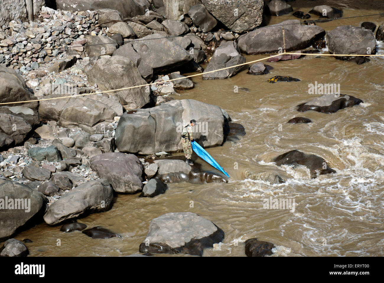 Border security force soldier washing plastic sheet in jhelum river ; Uri ; Baramulla ; Jammu and Kashmir ; India  6 April 2008 Stock Photo