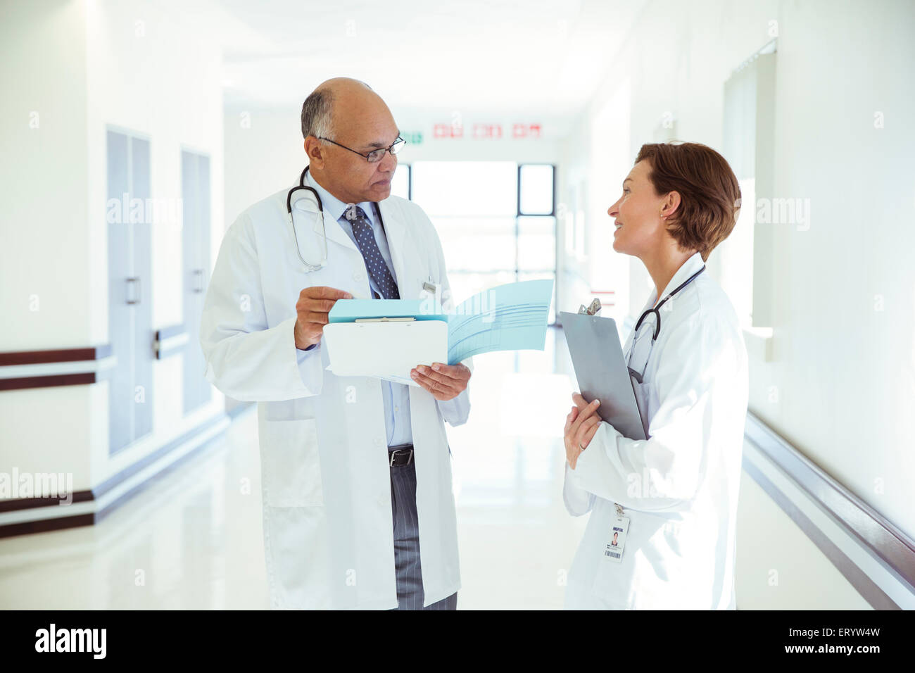 Doctors discussing medical record in hospital corridor Stock Photo