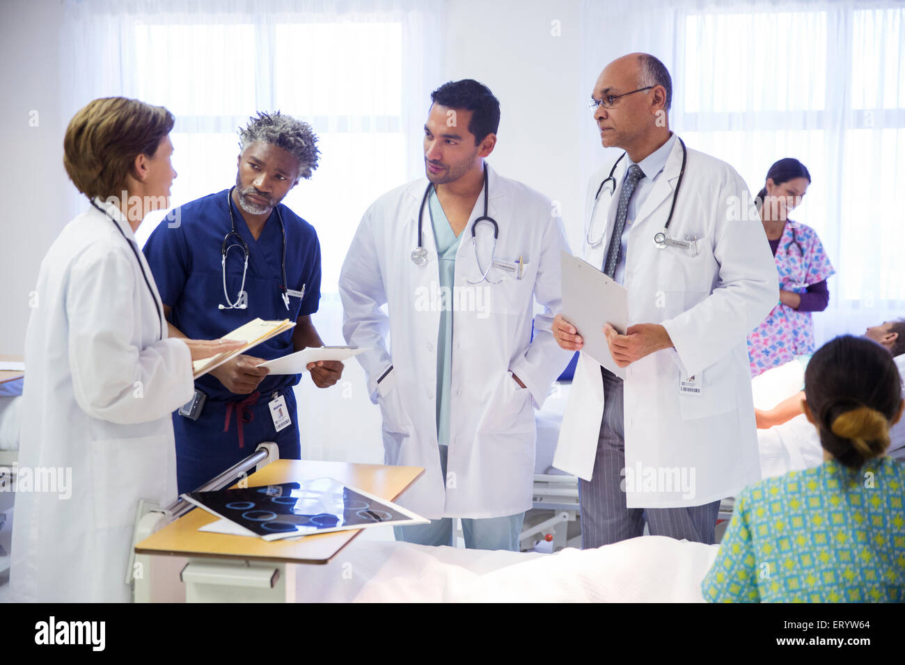 Doctors making rounds and consulting in hospital room Stock Photo