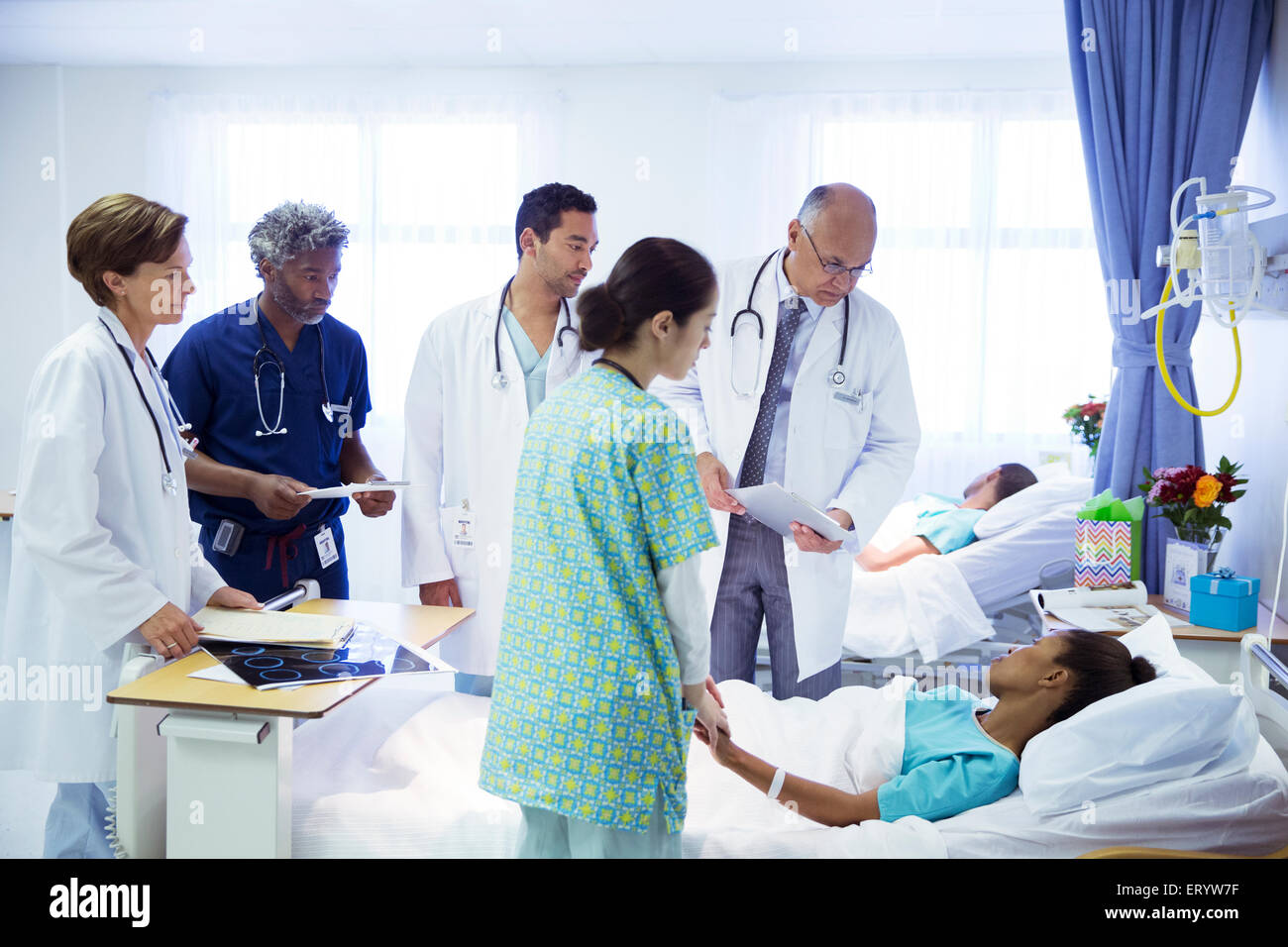 Doctors and nurse making rounds in hospital room Stock Photo