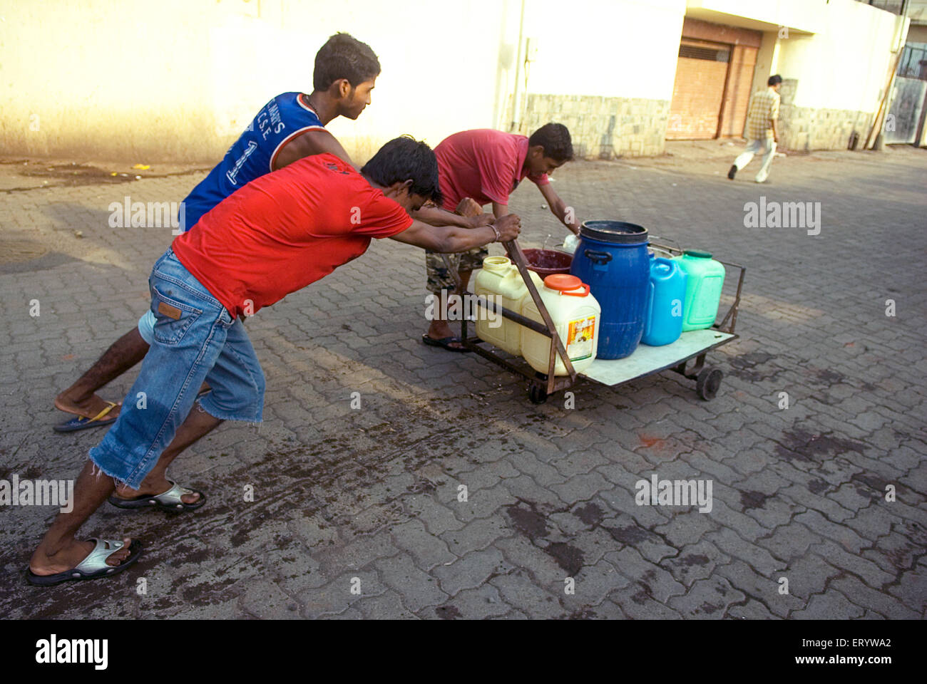 water shortage , boys pushing water jars on hand cart , Banganga , Walkeshwar , Bombay , Mumbai ; Maharashtra ; India , asia Stock Photo