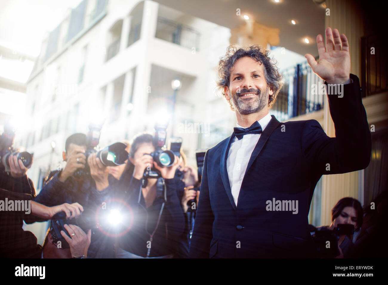 Celebrity waving to paparazzi photographers at event Stock Photo