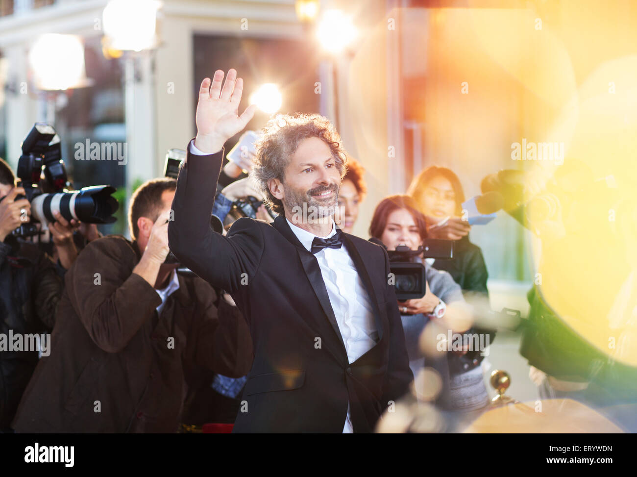 Celebrity waving for paparazzi at event Stock Photo