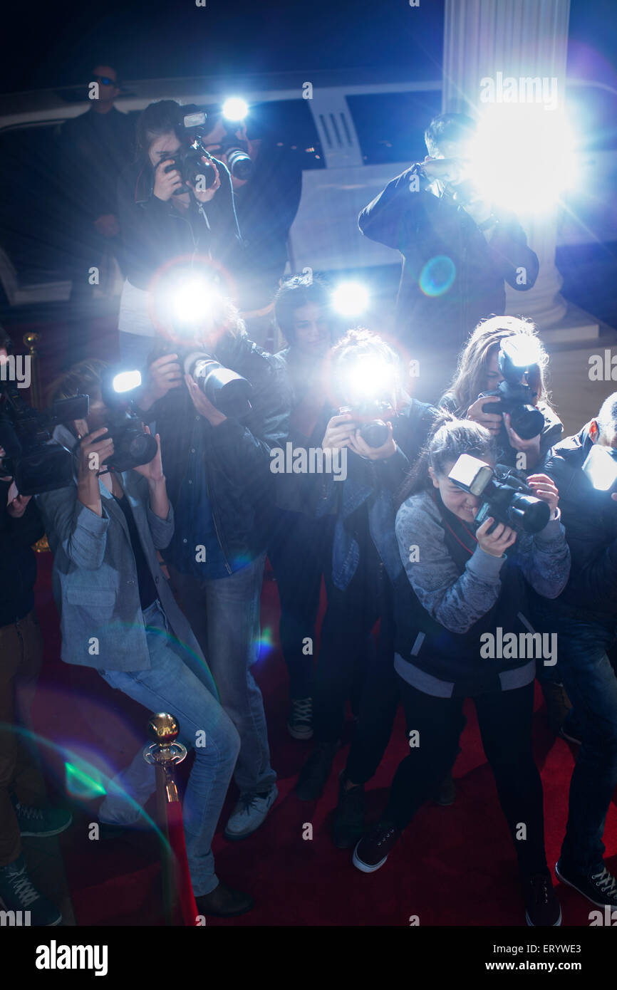 Paparazzi photographers pointing cameras at red carpet event Stock Photo