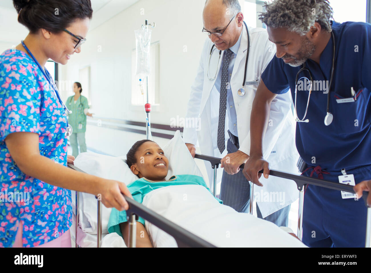 Doctors and nurse talking with patient on stretcher in hospital corridor Stock Photo