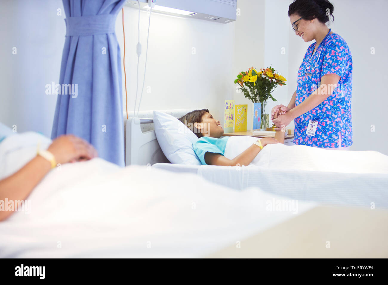 Nurse holding hands with patient in hospital room Stock Photo