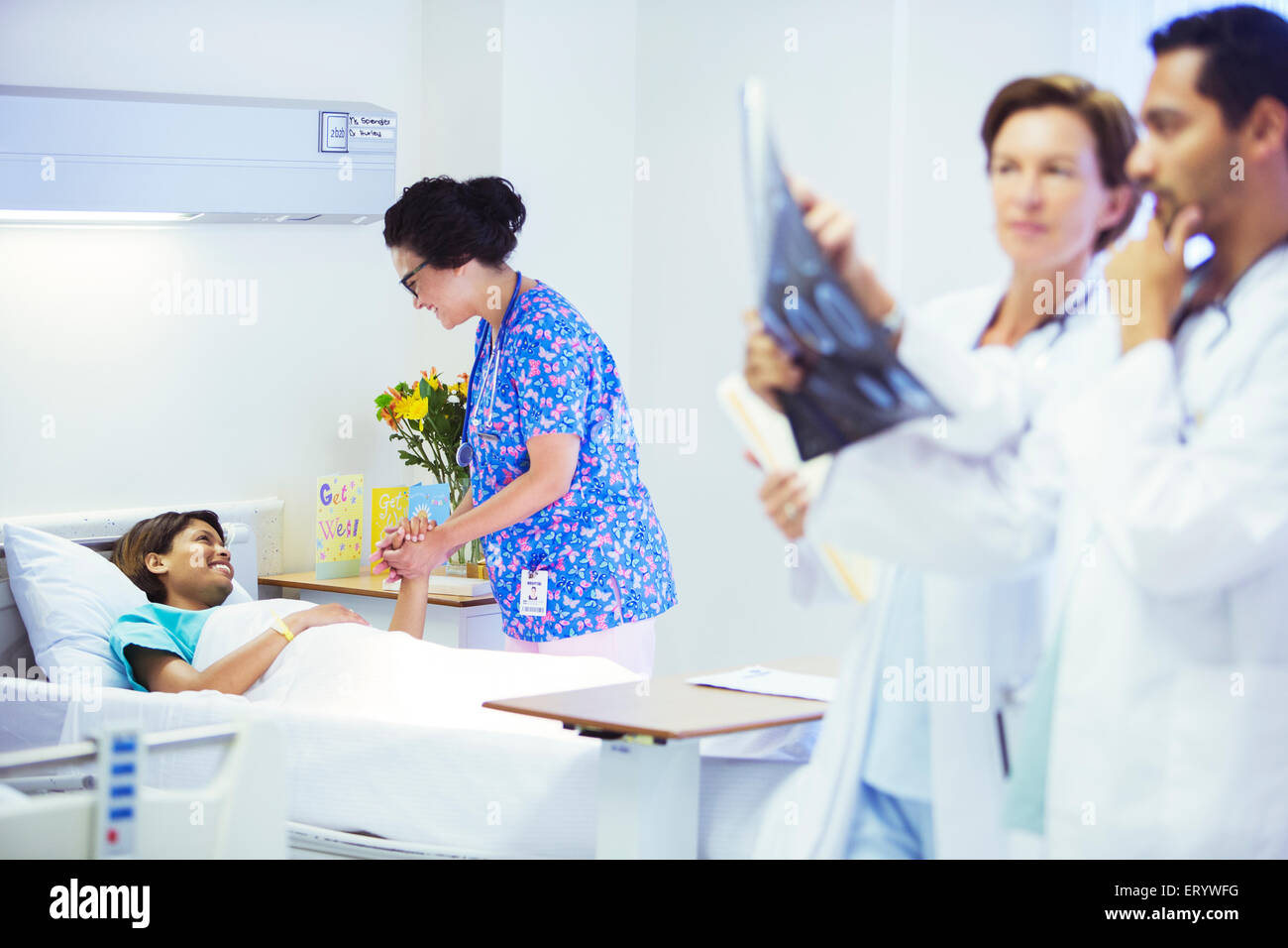 Nurse holding hands with patient in hospital room Stock Photo