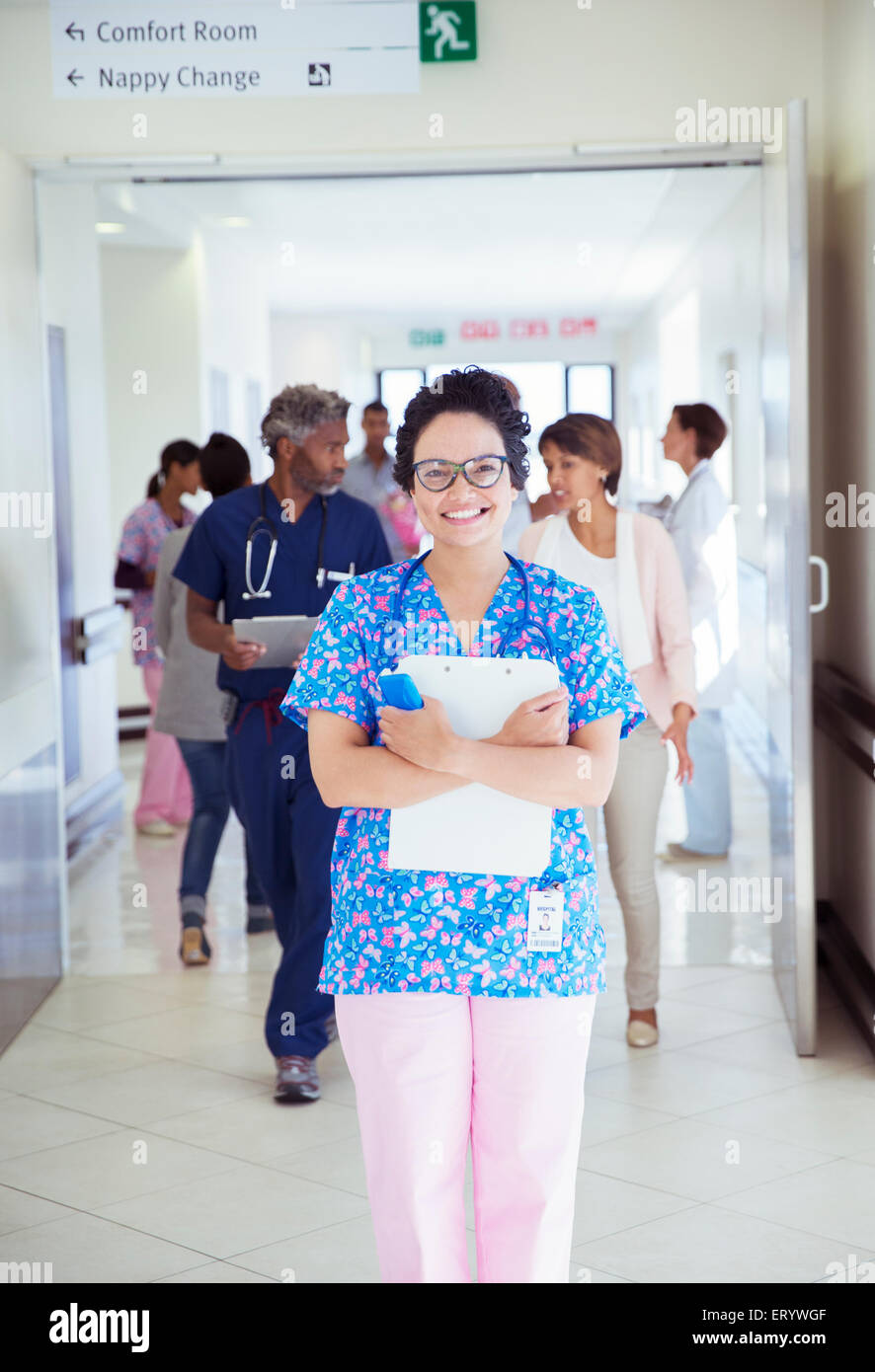 Portrait of confident nurse with clipboard in hospital corridor Stock Photo