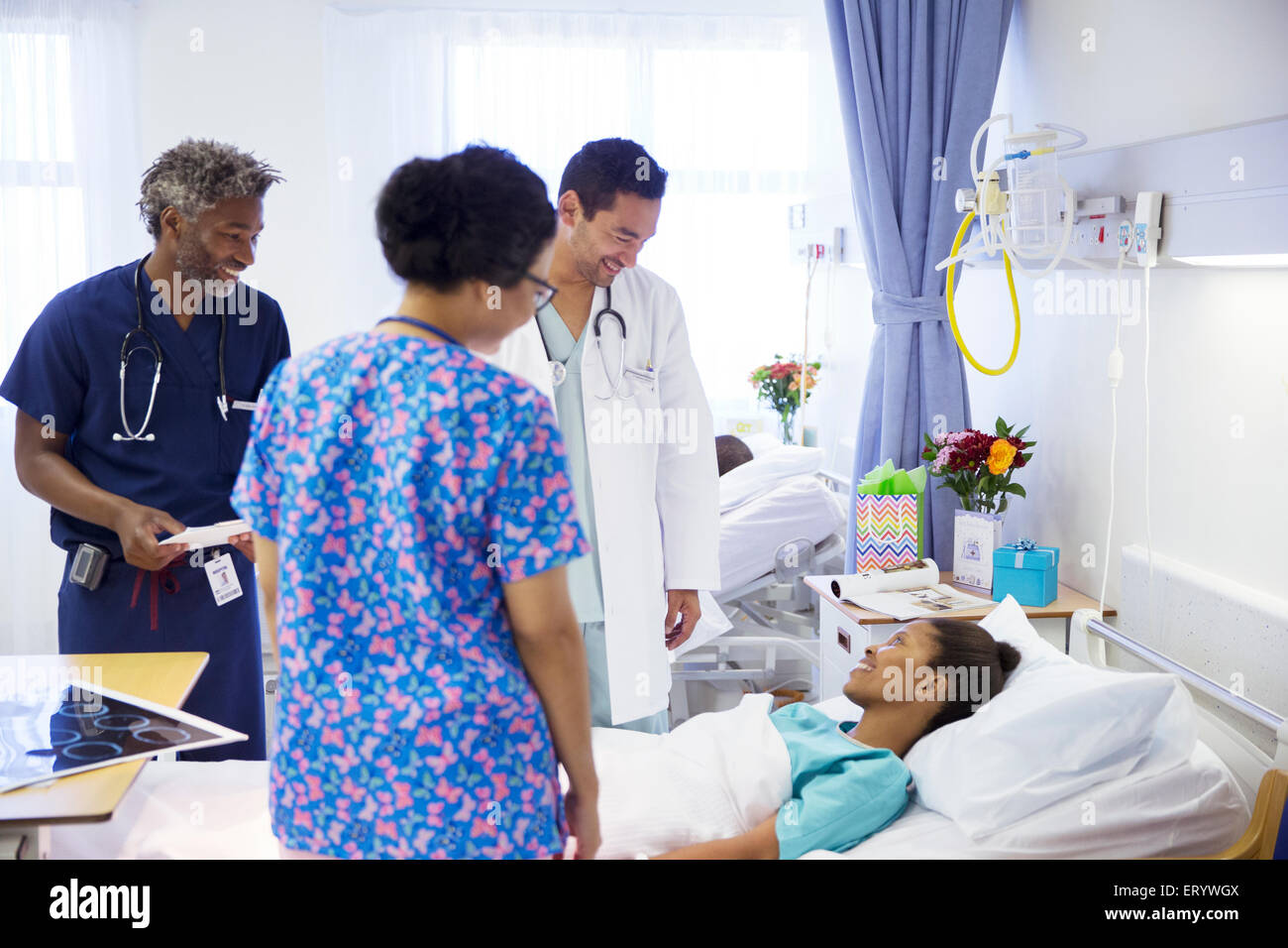 Doctors making rounds and talking with patient in hospital Stock Photo