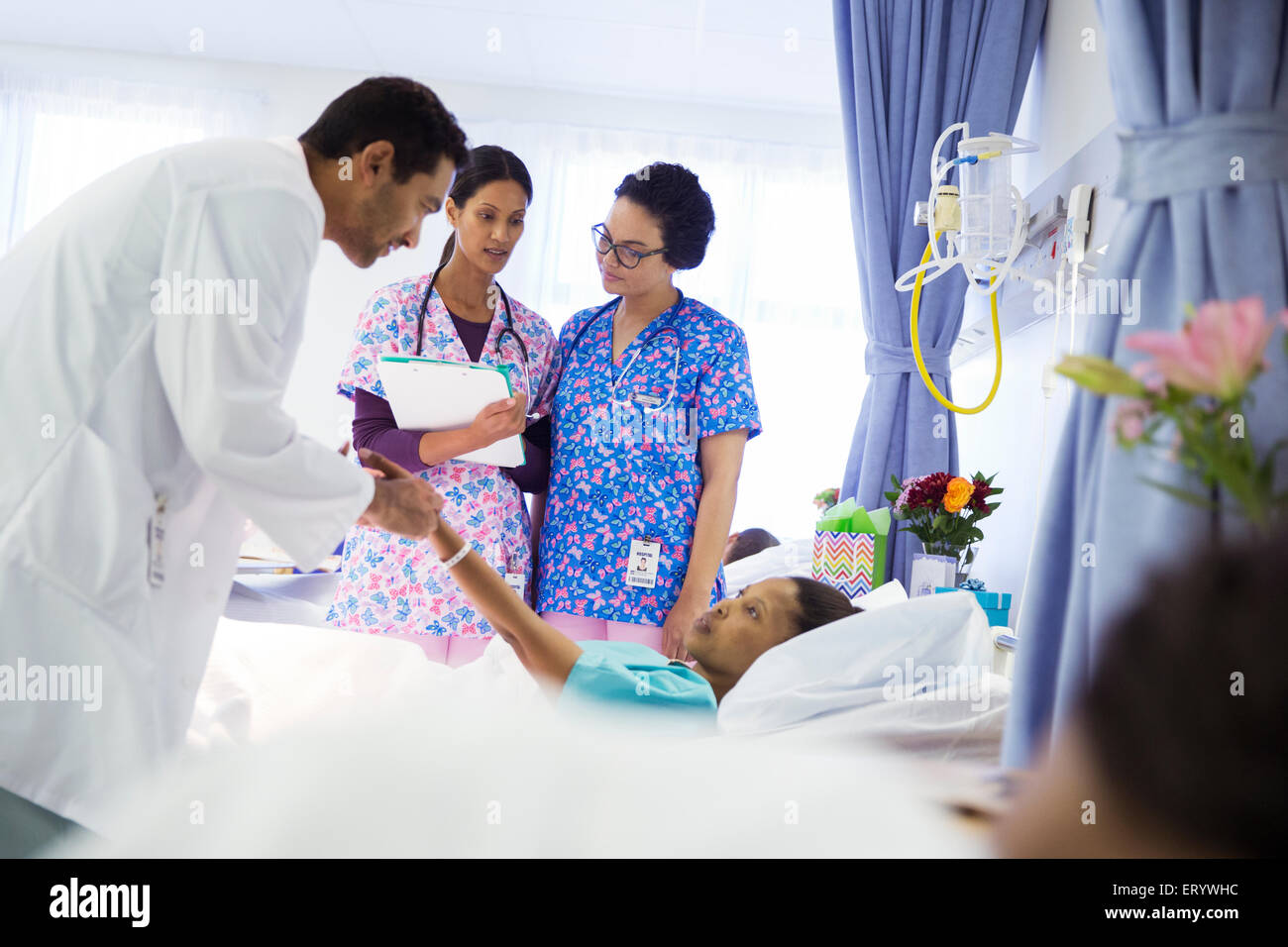 Doctor and nurses making rounds in hospital room Stock Photo