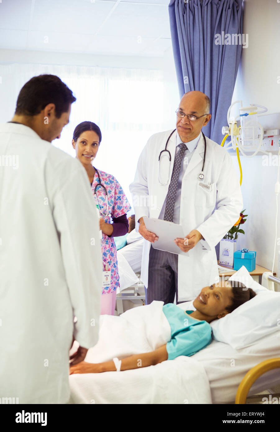 Doctors and nurse making rounds in hospital room Stock Photo