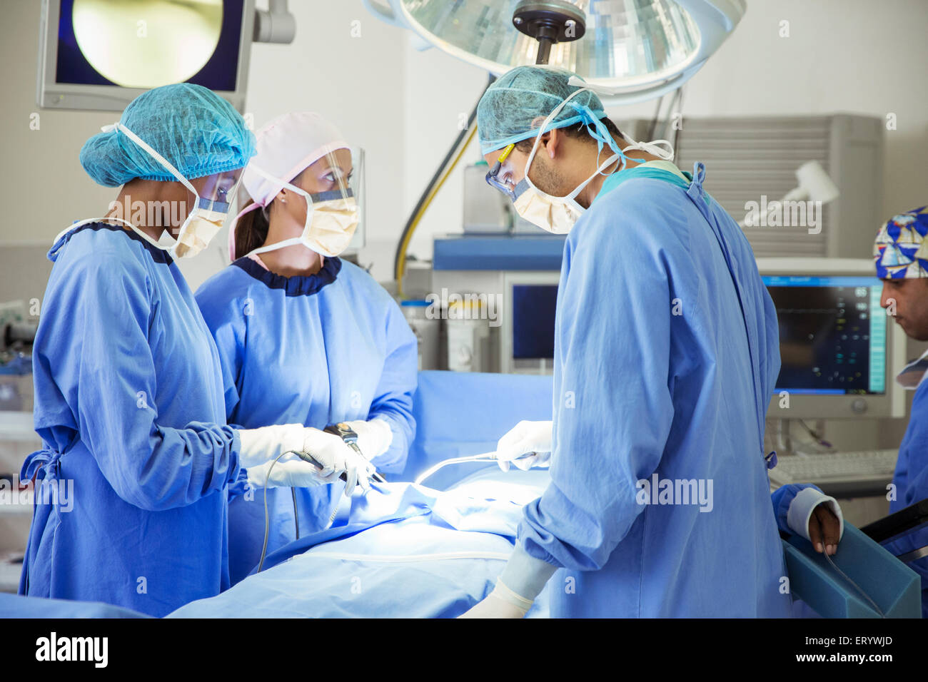 Surgeons performing surgery in operating room Stock Photo