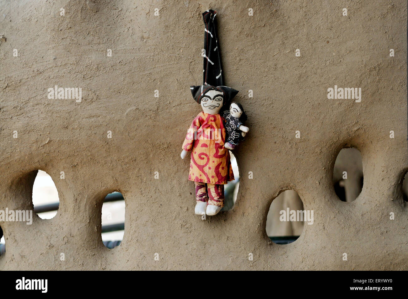 Stuff mini dolls hang on the mud wall ; Bhuj ; Kutch ; Gujarat ; India Stock Photo