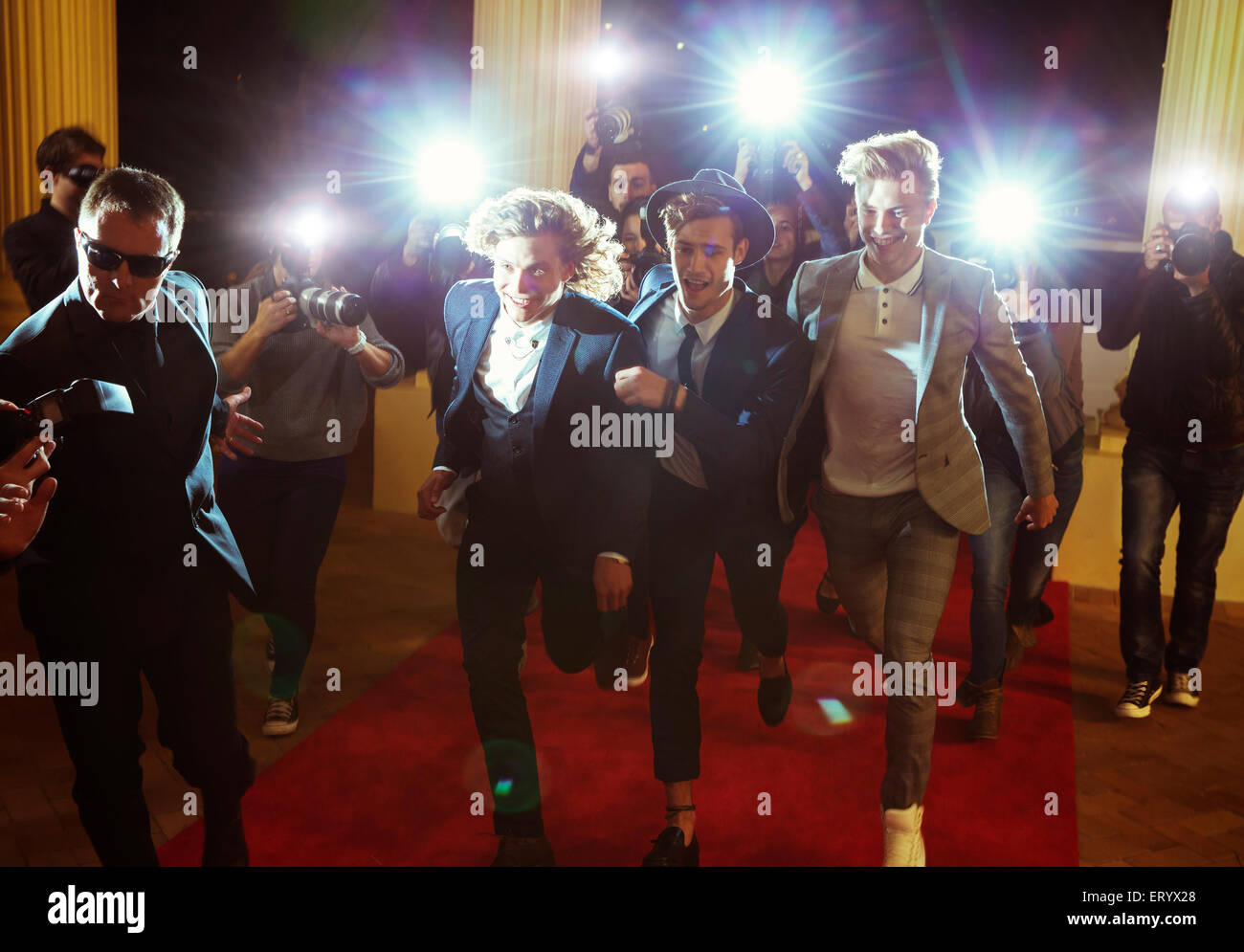 Celebrities running from paparazzi photographers at red carpet event Stock Photo