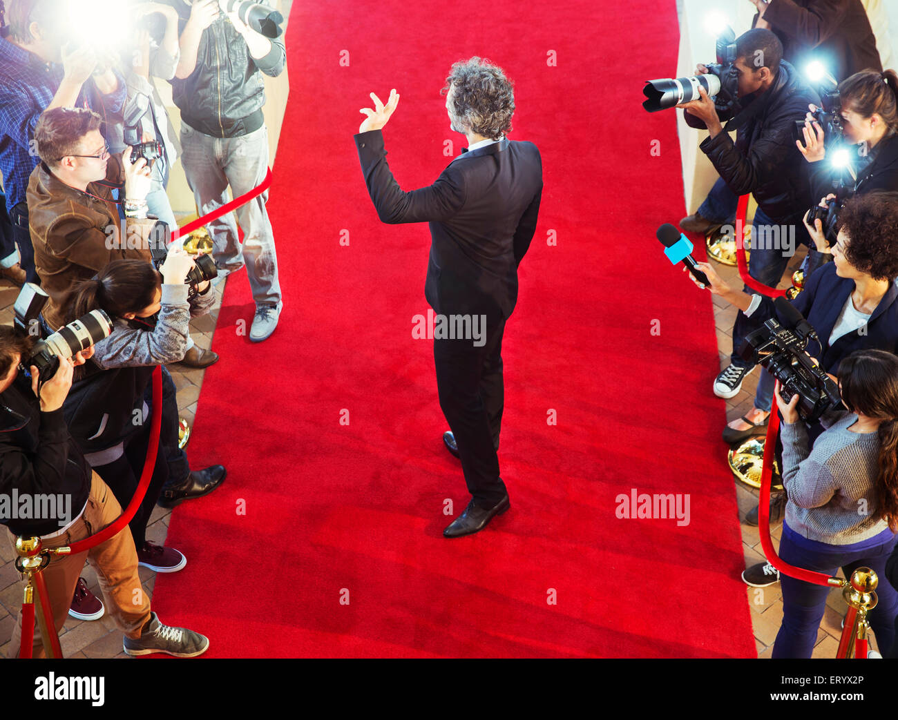 Celebrity arriving at red carpet event and waving at photographing paparazzi Stock Photo