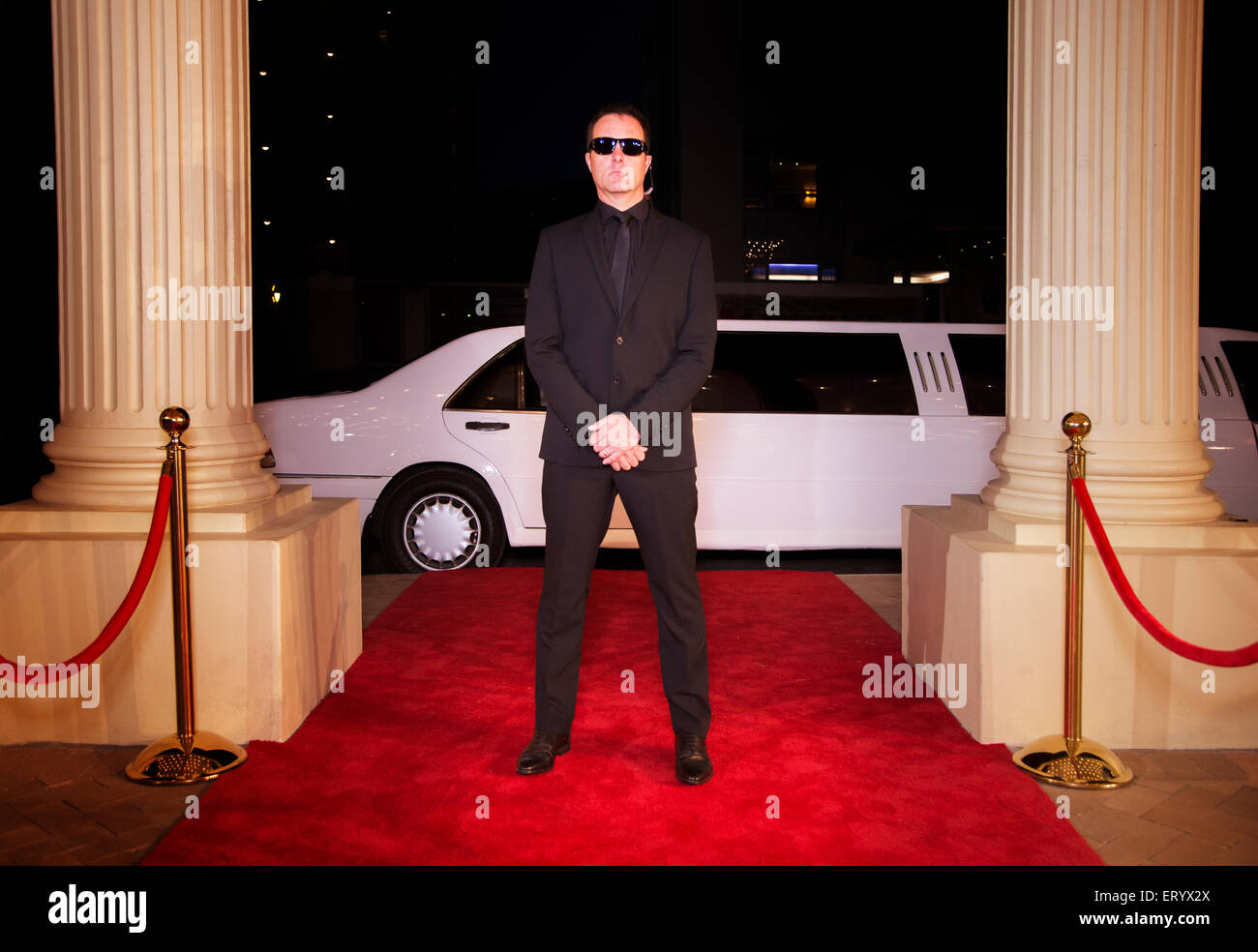 Serious bodyguard in sunglasses protecting red carpet at event Stock Photo