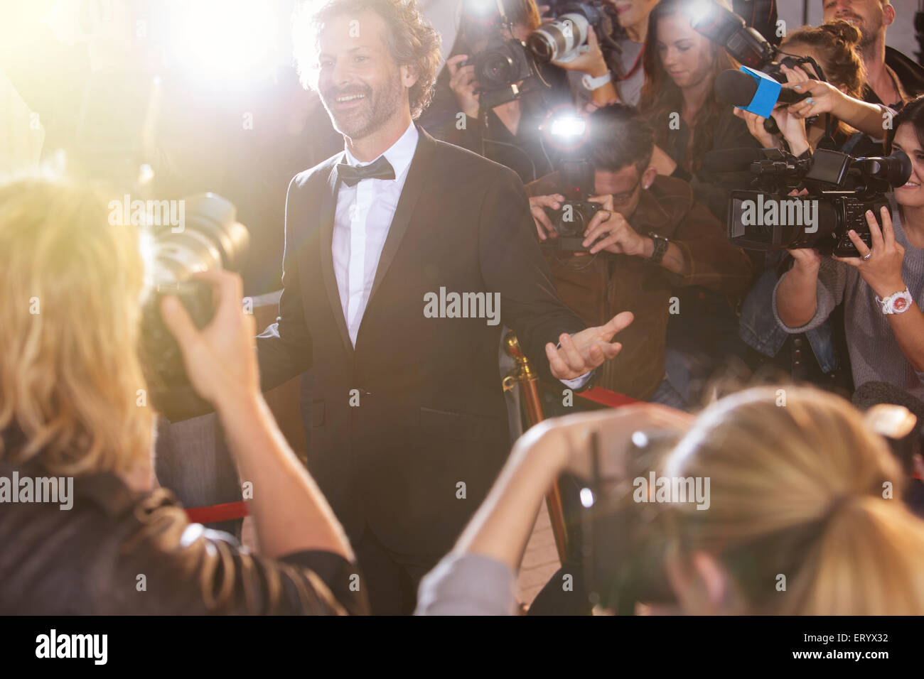 Smiling celebrity posing for paparazzi photographers at event Stock Photo