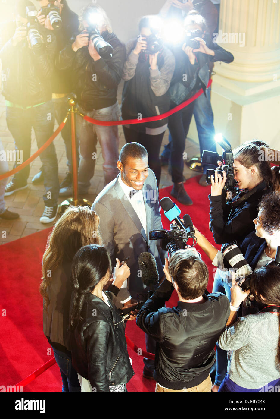 Celebrity being interviewed and photographed by paparazzi photographer at red carpet event Stock Photo