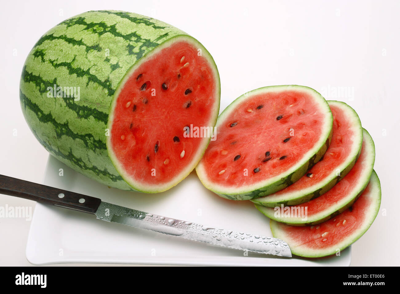 Fruits ; Water Melon Latin Citrullus Lanatus slices and knife on a tray Stock Photo