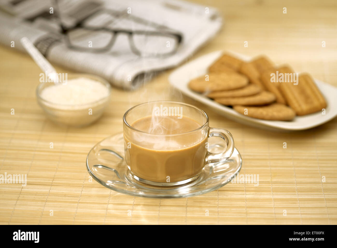 tea with sugar biscuits newspaper and spectacle Stock Photo