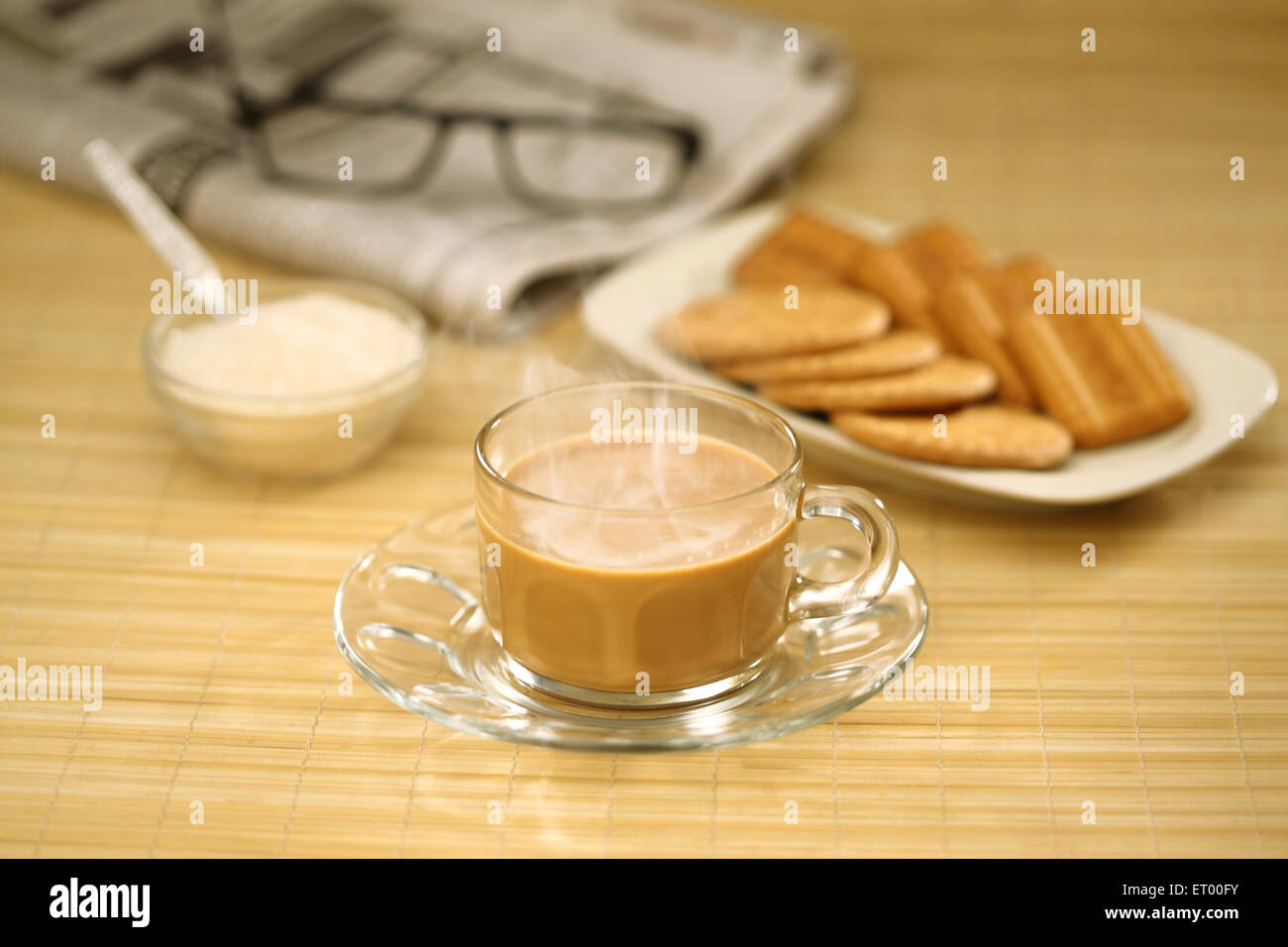 tea with sugar biscuits newspaper and spectacle Stock Photo