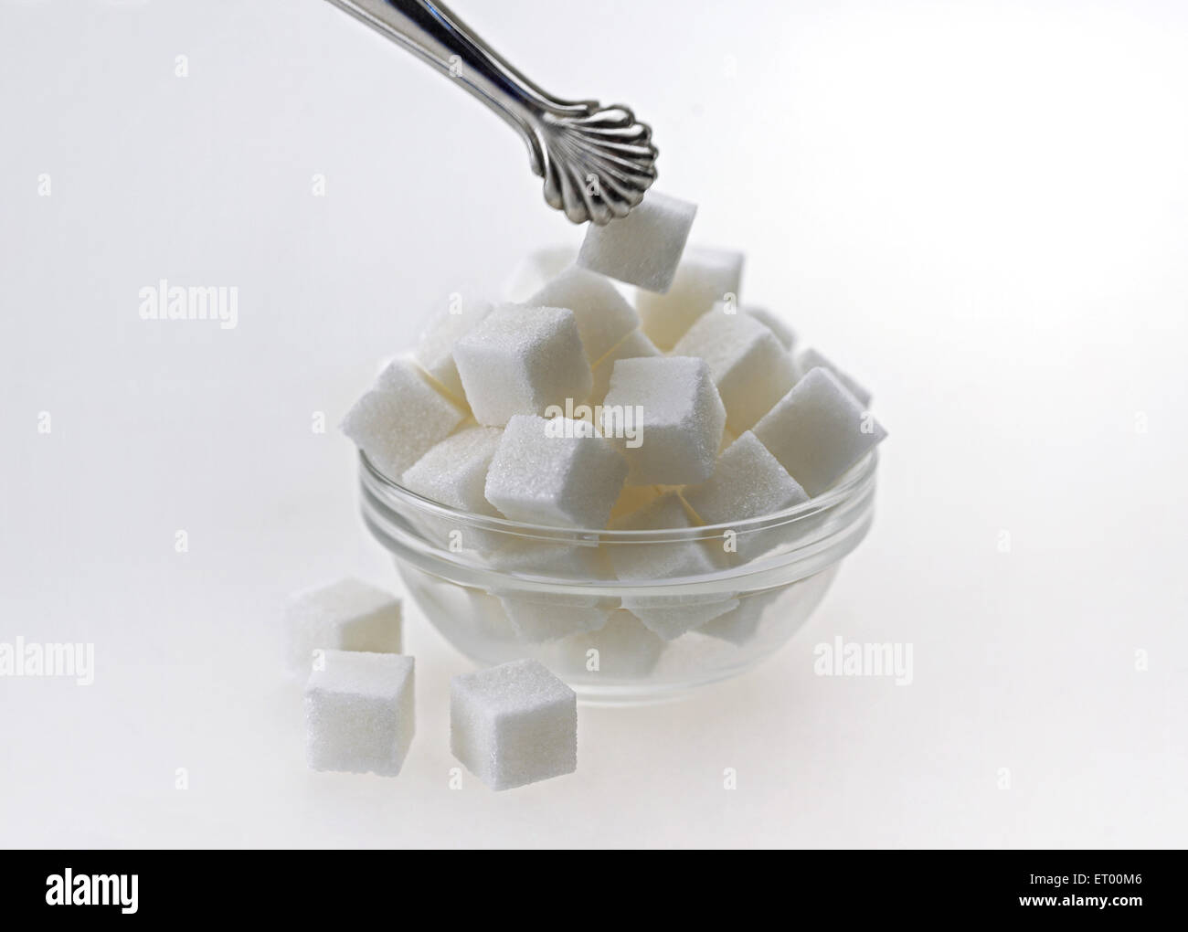 Sugar cubes in a glass bowl with tongs Stock Photo