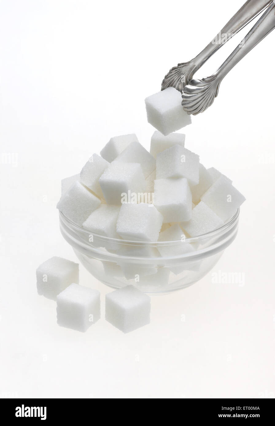 Sugar cubes in a glass bowl with tongs Stock Photo