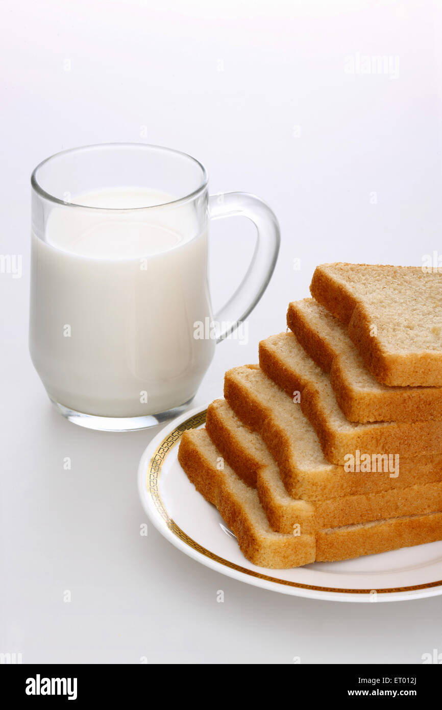 Slices of brown bread on a plate with a mug of milk Stock Photo