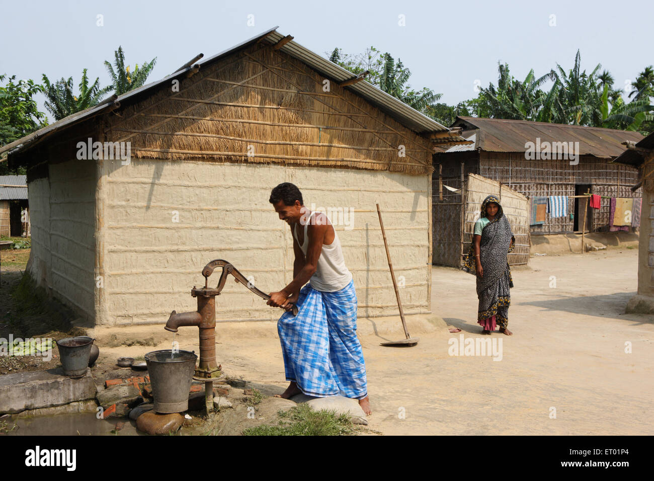 Man using hand pump in village ; Assam ; India NOMR Stock Photo