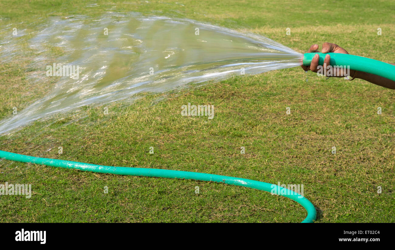 Watering of lawn by garden hose Stock Photo