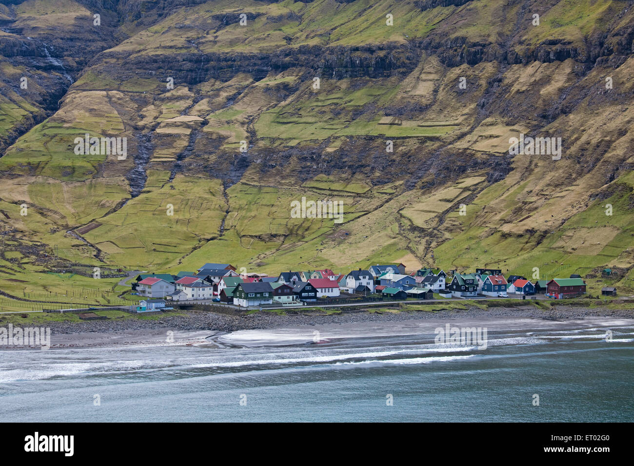 Coastal village below green cliffs, Tjornuvik, Faroe Islands Stock Photo