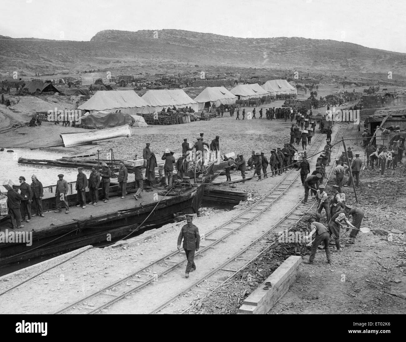 Soldiers making up a fatigue party seen here landing stores from a lighter whilst engineers construct a light railway at 'A' West Beach, Suvla Point. Circa May 1915 Stock Photo