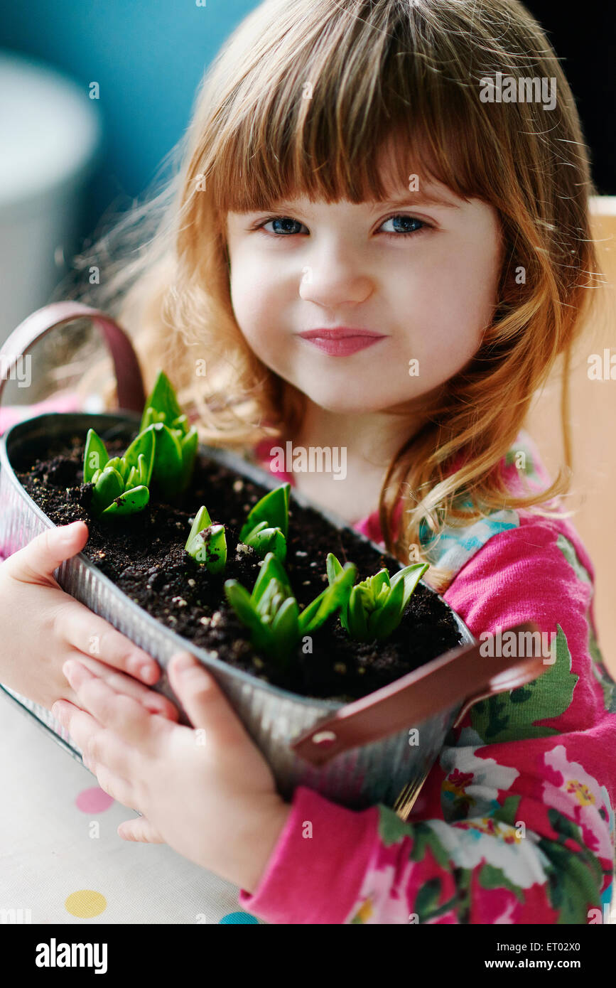 Close up portrait of girl holding sprouting flowers in basket Stock Photo