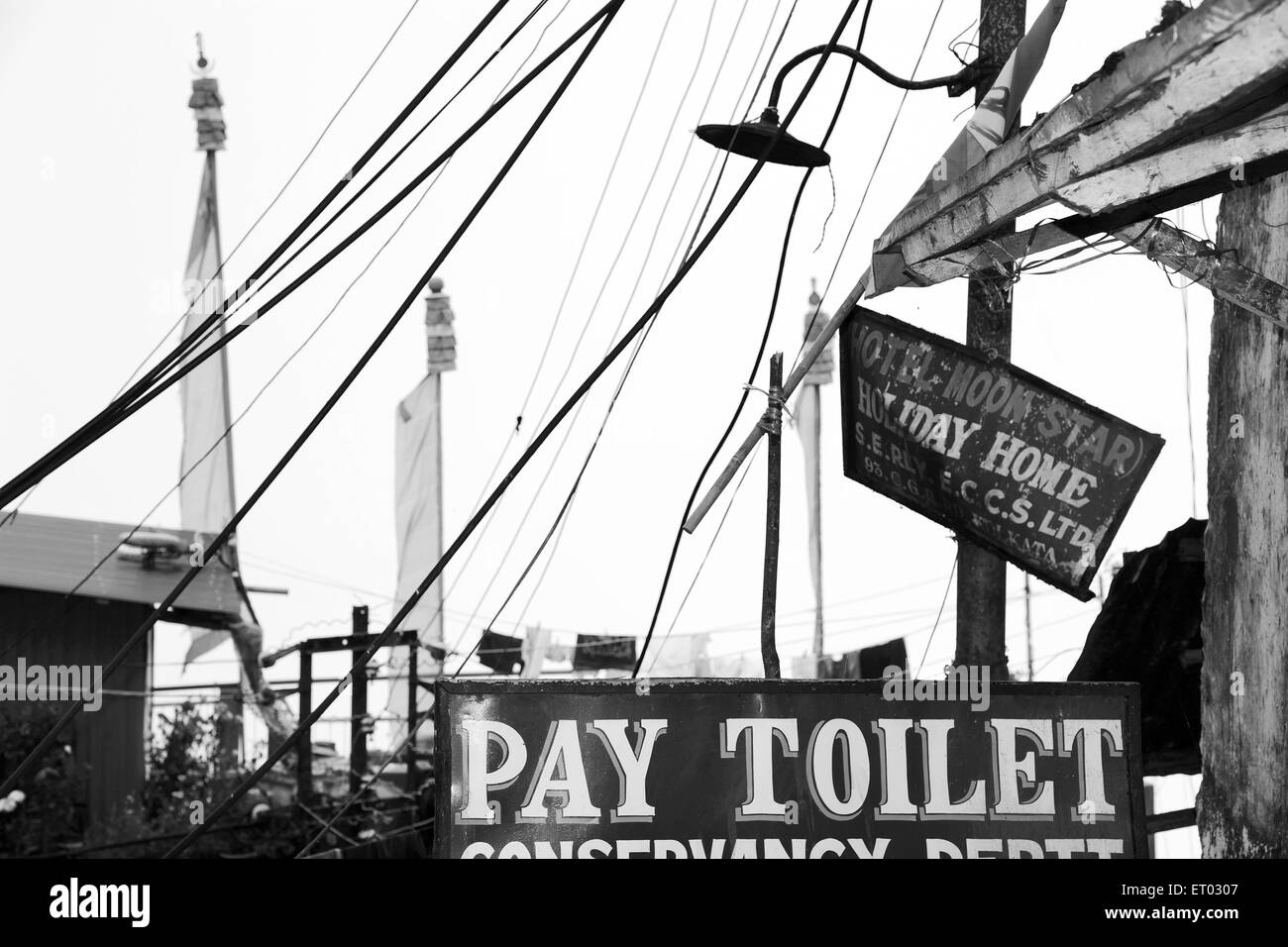 Wires hanging and pay toilet sign and Buddhist prayer flags , Darjeeling , West Bengal India , 2011 Stock Photo