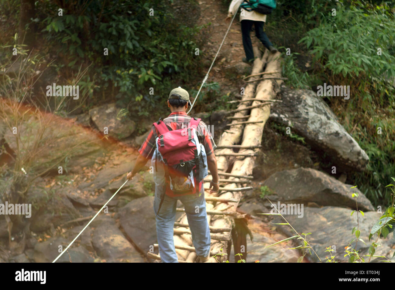 Trekker crossing rickety bridge , Coorg , Madikeri , hill station , Kodagu district , Western Ghats , Karnataka , India , Asia Stock Photo