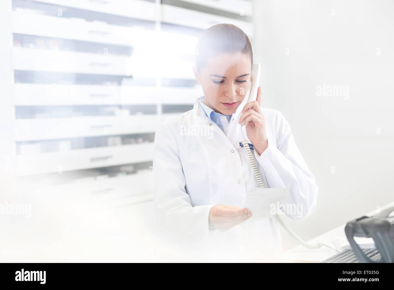 Pharmacist verifying prescription on telephone in pharmacy Stock Photo