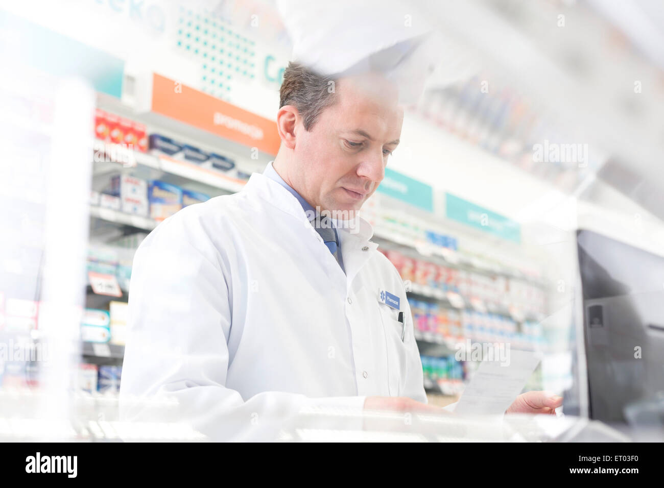 Pharmacist reviewing prescription at computer in pharmacy Stock Photo