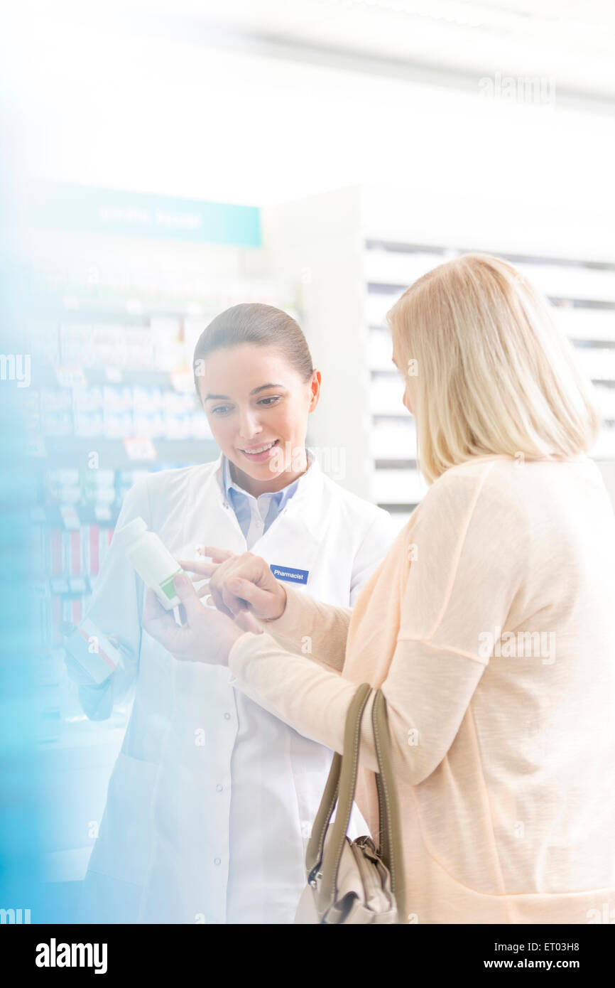 Pharmacist and customer reviewing label on bottle in pharmacy Stock Photo