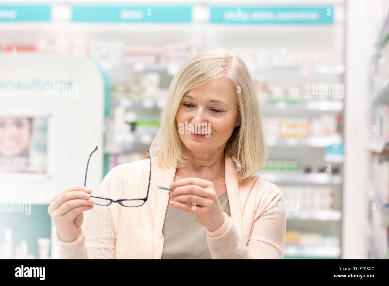 Customer looking at price tag on reading glasses in pharmacy Stock Photo