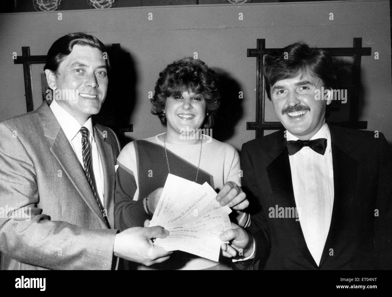 Patrons at Maximillian's nightclub in Birmingham have raised just over £2,300 for young Worcester boy, Andrew Combs, who was horrifically burned at his home. Head doorman Gerald Smith is pictured handing over the cheque with wine bar manageress Catherine Perruzza to fund trustee Mr Alois Gough. 15th August 1985. Stock Photo