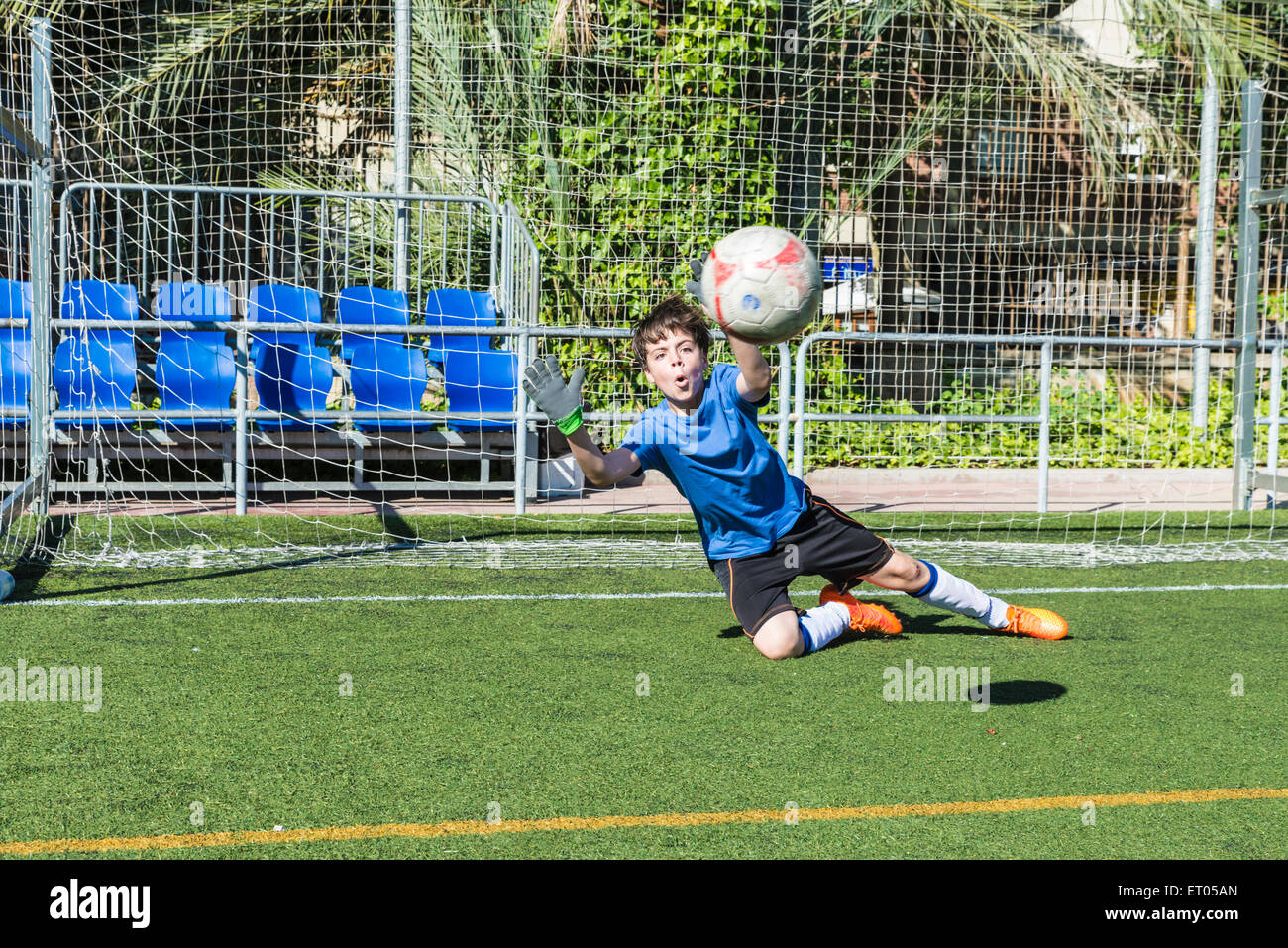 Young football goalkeeper stretching to stop a ball Stock Photo