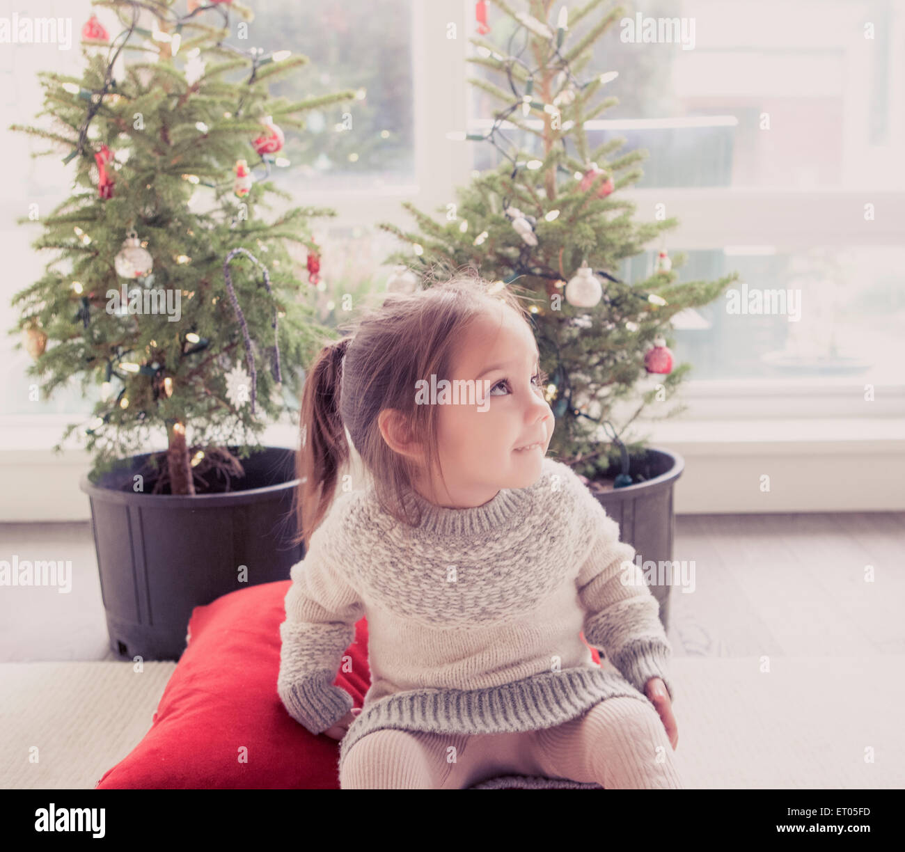 Smiling girl in front of potted trees with Christmas lights Stock Photo