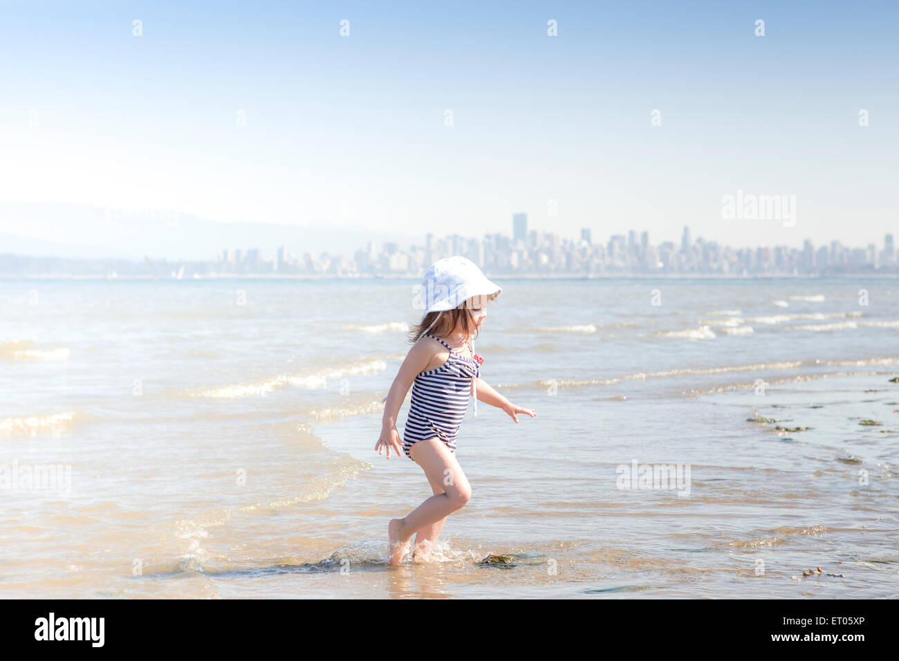 Girl wading in surf on beach Stock Photo