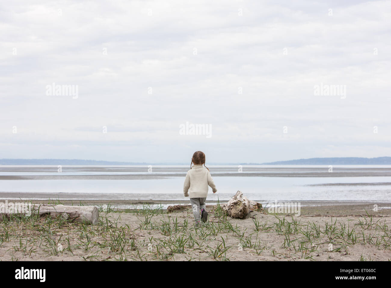 Girl running toward ocean on beach Stock Photo